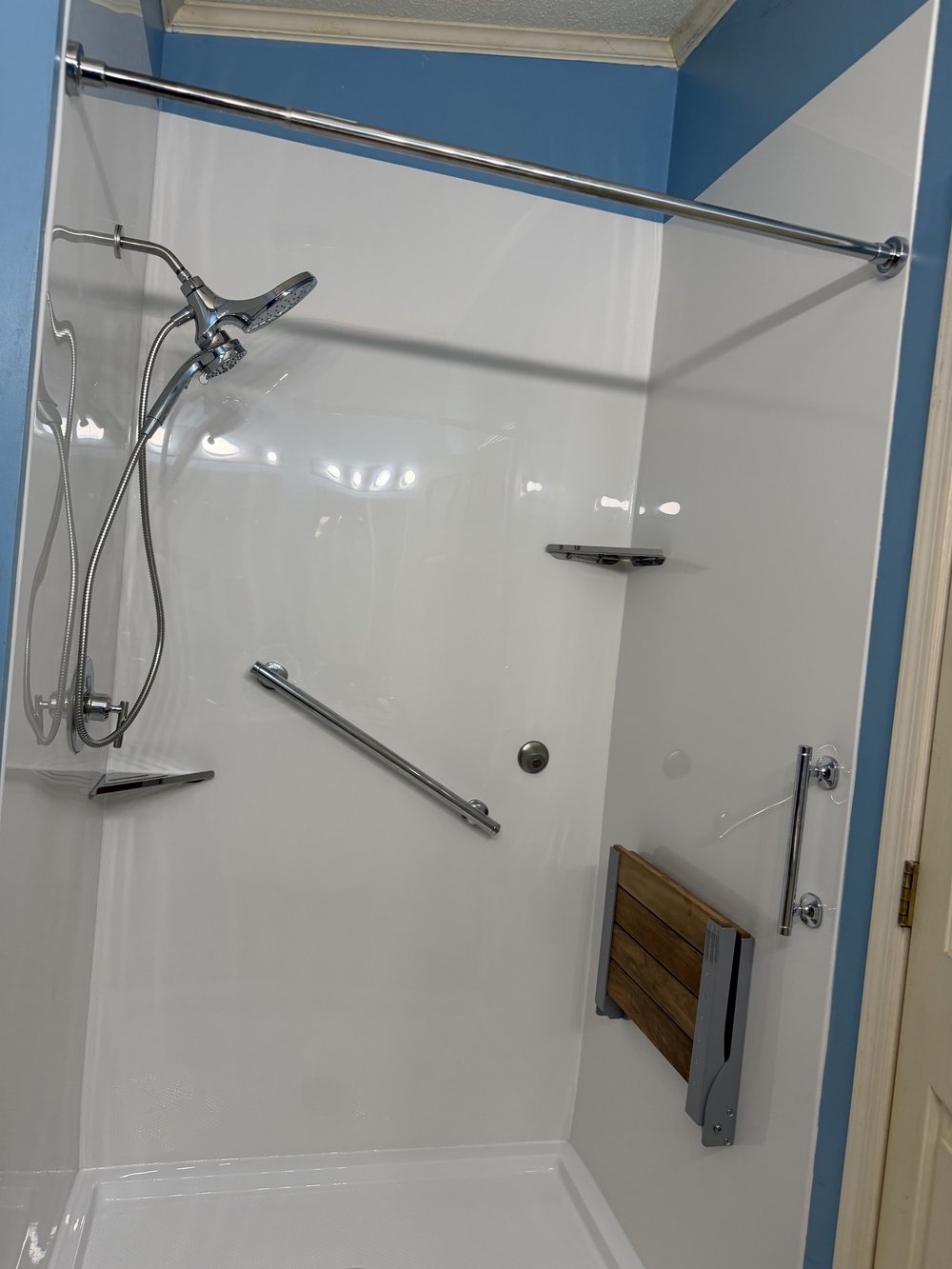 A real Revive Bath Co walk-in shower with grab bars and a fold-down seat